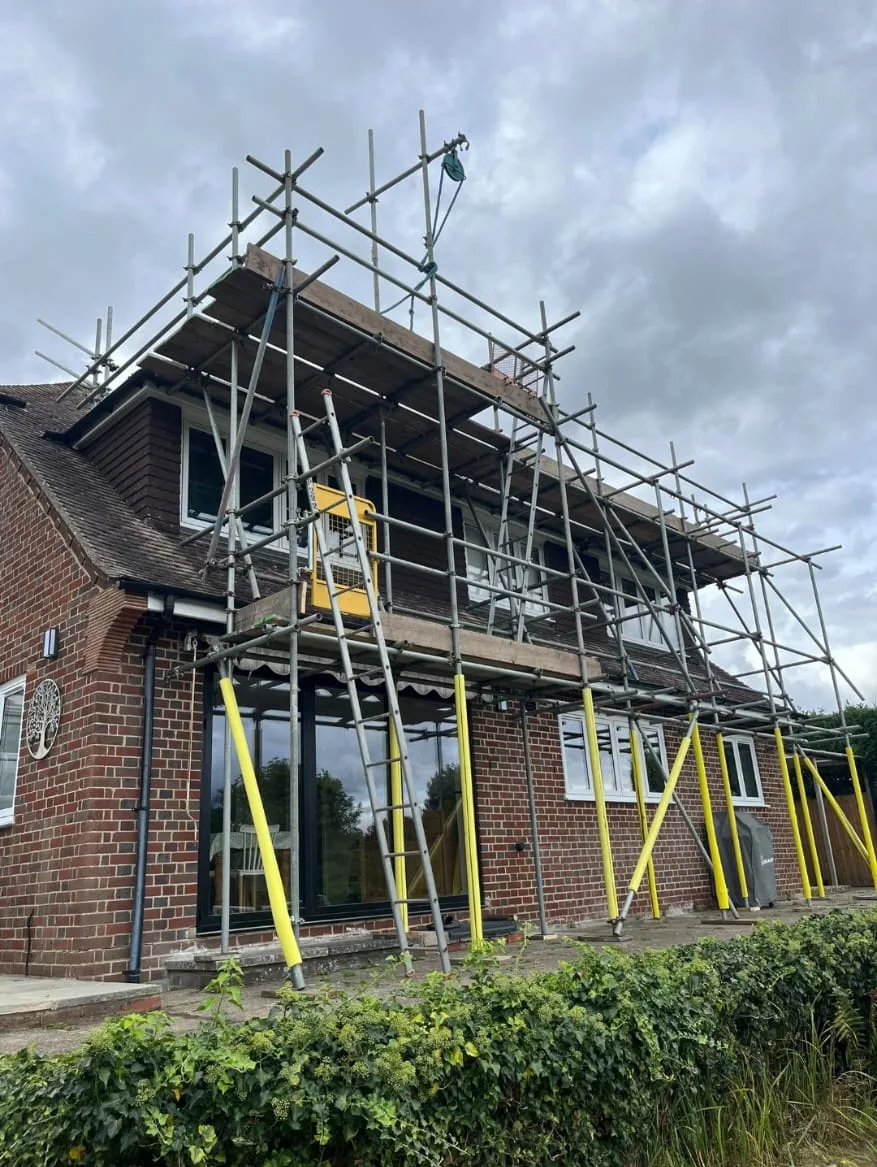 Rear scaffold access around a brick house with a dormer roof