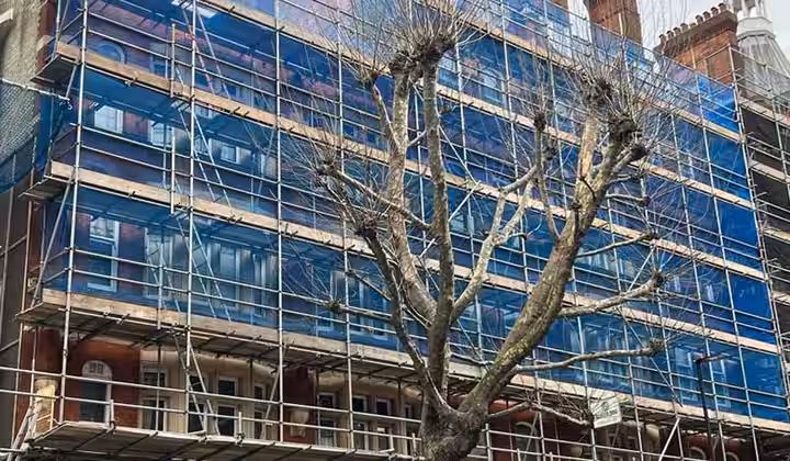 Scaffolding with blue protective sheeting across a building frontage