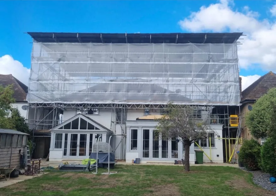 Temporary roof scaffold and protective sheeting above the rear of a house