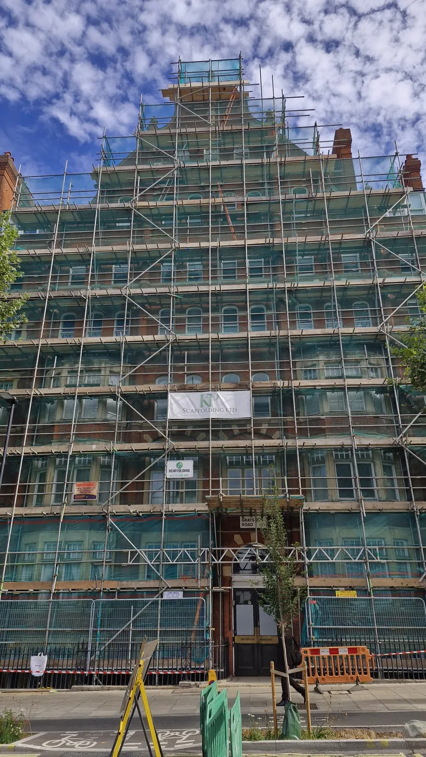 Full height scaffolding and green safety netting across a Central London brick building with KP Scaffolding banners